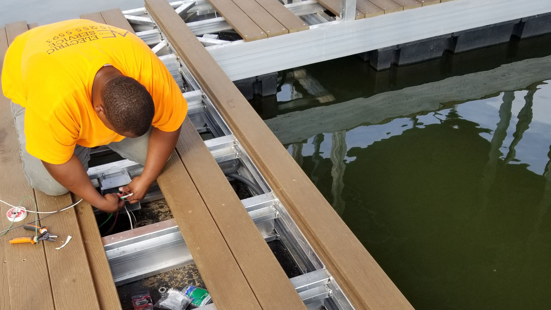 Amprite electrician wiring a dock junction box on a floating aluminum dock