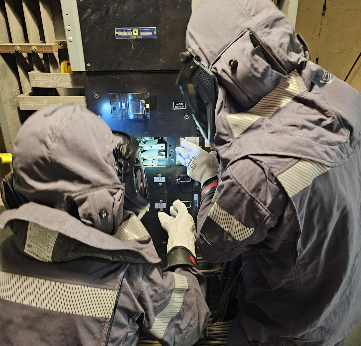 Technician in arc flash PPE performing a scheduled infrared inspection on switchgear