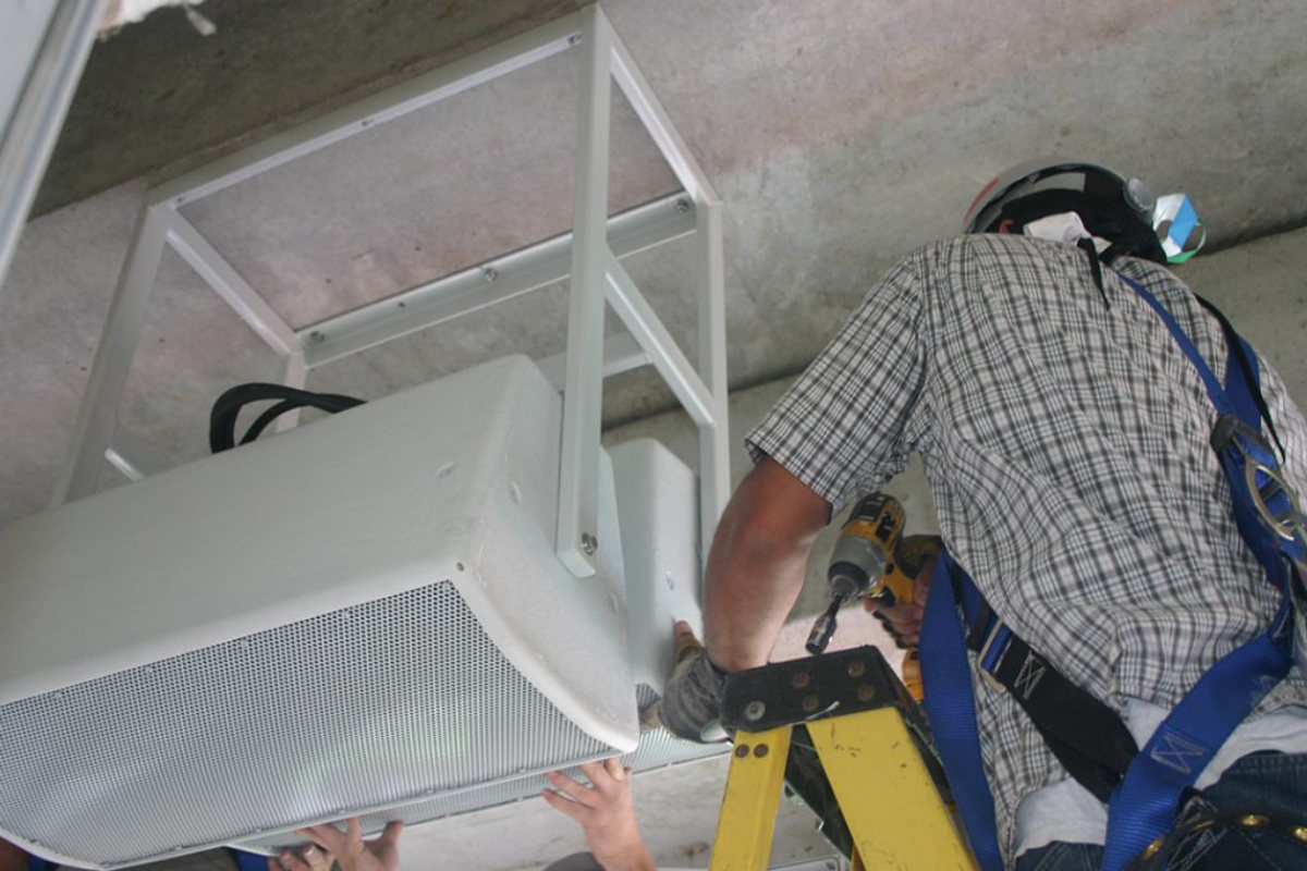 Amprite technician mounting a speaker enclosure at Nissan Stadium