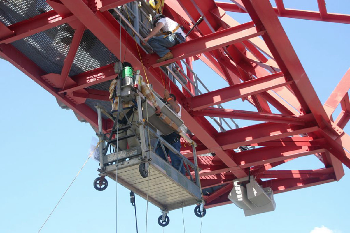Crew rigging speakers from the roof truss at Nissan Stadium