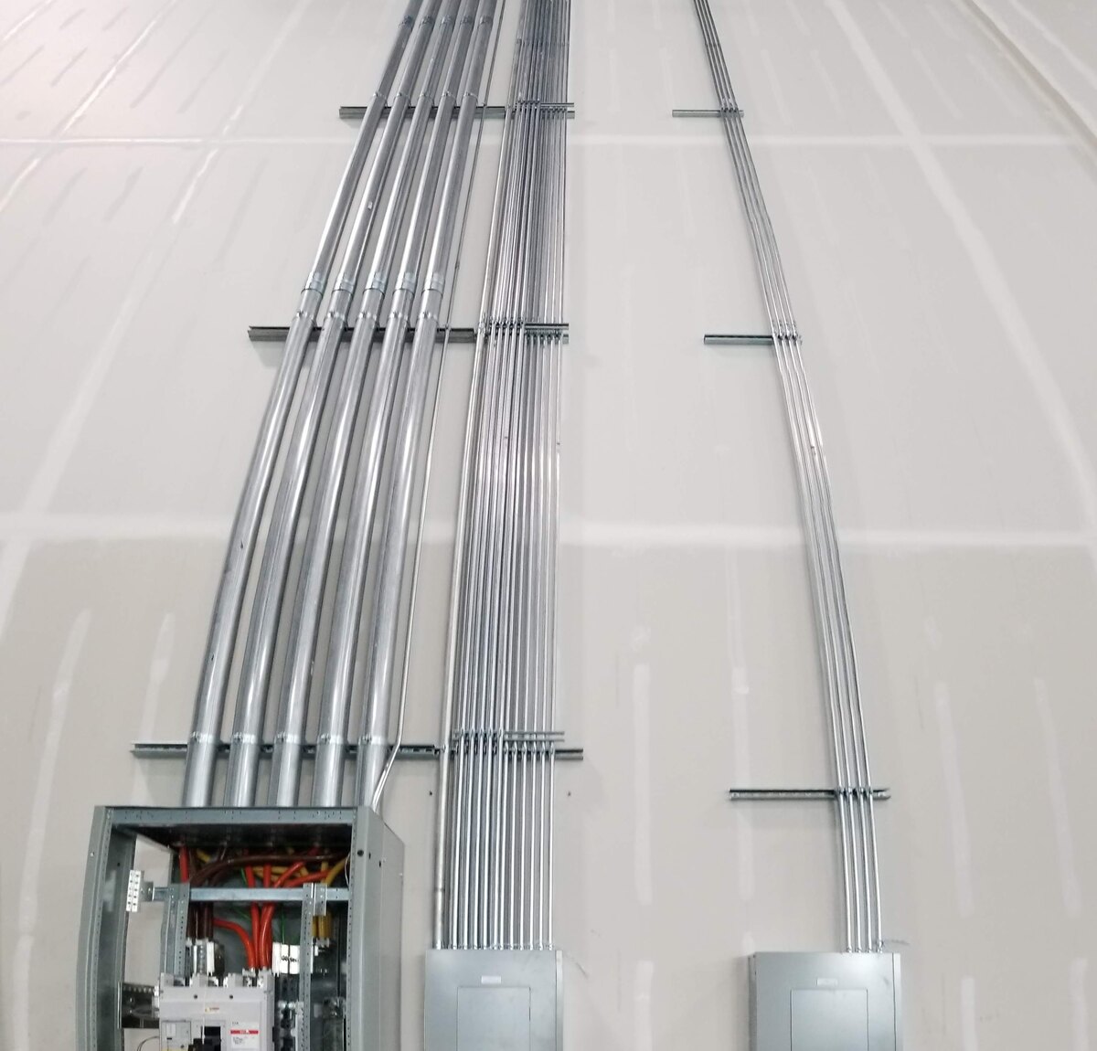Conduit bank rising to distribution panels during an industrial electrical installation by Amprite