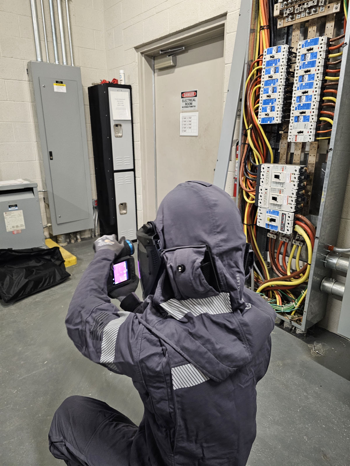 Technicians in arc flash rated PPE performing infrared thermography on electrical equipment