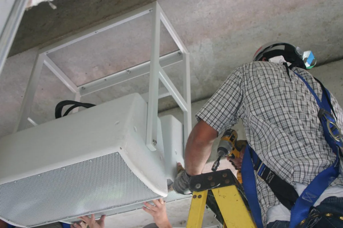 Amprite technician mounting a speaker enclosure at Nissan Stadium