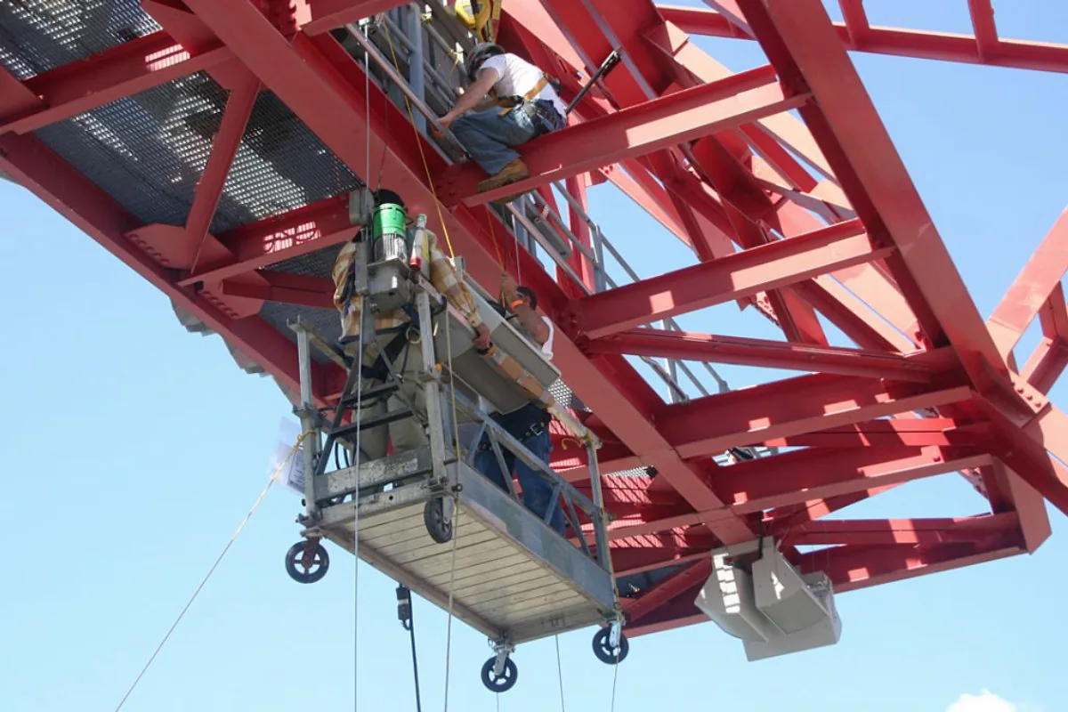 Crew rigging speakers from the roof truss at Nissan Stadium