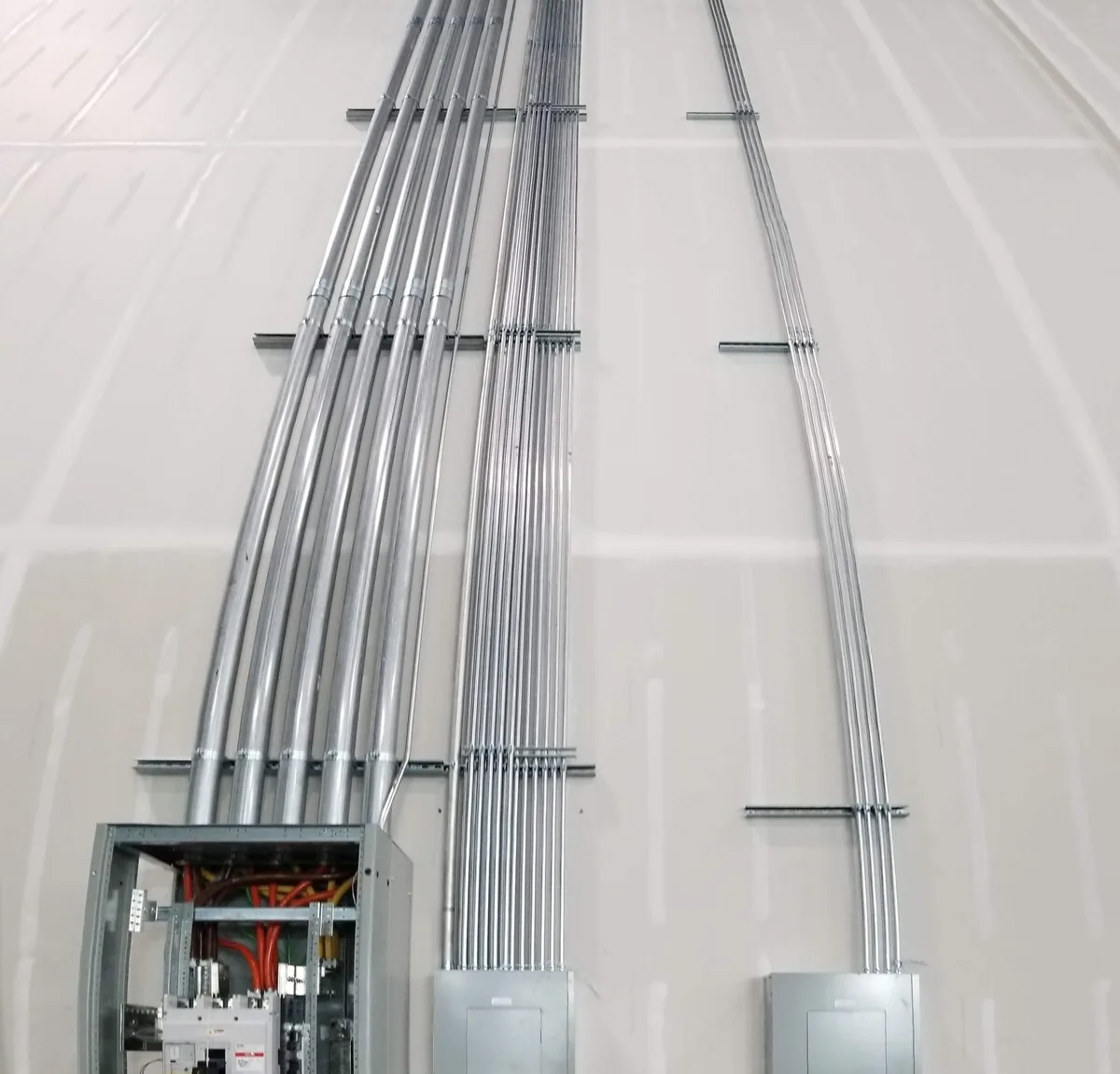 Conduit bank rising to distribution panels during an industrial electrical installation by Amprite